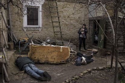 Ira Gavriluk holds her cat as she walks past the bodies of her husband, brother and another man, who were killed outside their home in Bucha, on the outskirts of kyiv.