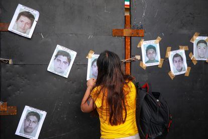 Una manifestante pega fotografías de los estudiantes desaparecidos de Ayotzinapa.