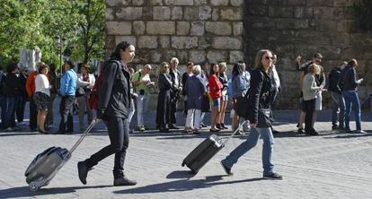 Dos mujeres pasan con sus maletas junto al Alc&aacute;zar de Sevilla.