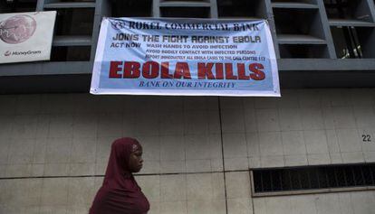 Una mujer pasa bajo un cartel con recomendaciones para hacer frente al ébola en Freetown (Sierra Leona).