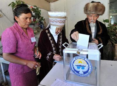 Una pareja ataviada a la manera tradicional vota en Bishkek en presencia de una interventora.
