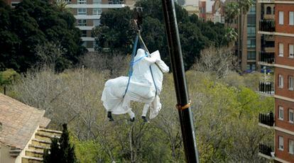 Una grúa eleva la escultura ecuestre de Franco tapada con una sábana para su traslado a Bétera.