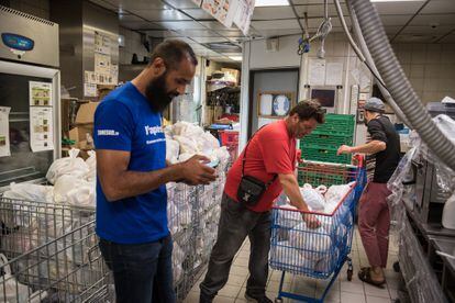 Kamel Guemari (izquierda), antiguo empleado de McDonald's, prepara bolsas de comida para su distribución junto a dos voluntarios.