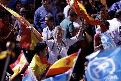 Una simpatizante del PP ondea dos banderas de España durante la celebración en la sede del partido en Génova.