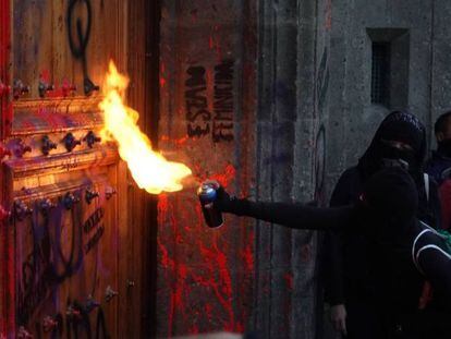 Un grupo de mujeres pintan y queman la puerta de Palacio Nacional, este viernes en Ciudad de México. En video, aspectos de las protestas.