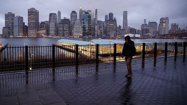 Un hombre camina por una calle desierta ante el 'skyline 'de Manhattan. En vídeo, Nueva York se vacía por el coronavirus, y el gobernador y el alcalde señalan a Trump.