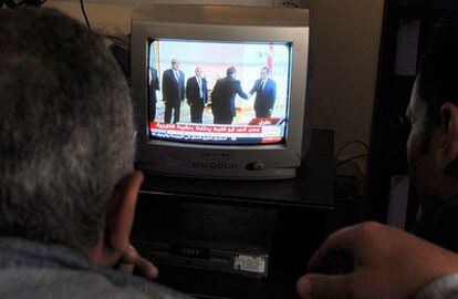 Un hombre egipcio sigue por televisión la toma de posesión de los nuevos ministros, que saludan al presidente Hosni Mubarak (a la derecha en la pantalla) en El Cairo.
