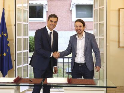 Spain's Prime Minister Pedro Sanchez, centre, shakes hands with the leader of the Podemos party Pablo Iglesias at the Moncloa Palace in Madrid, Spain, Thursday Oct. 11, 2018. Spain's Socialist minority government has agreed with the anti-austerity party Podemos to raise the country's minimum wage and increase taxes for the rich if next year's national budgets get parliamentary approval. Passing the 2019 national budget is seen as a key threshold for Prime Minister Pedro Sanchez's plans to remain in office until the current term ends in 2020. (Fernando Calvo/Pool Photo via AP)