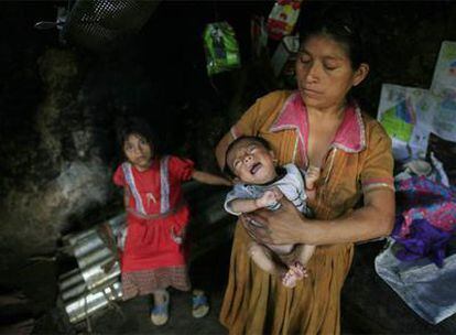 Una mujer con su hijo de seis meses en una casa de adobe de la aldea de Taiquezal.