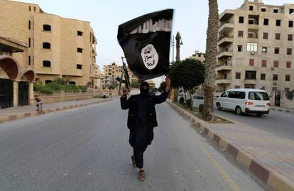 Un yihadista levanta la bandera del Estado Isl&aacute;mico en Raqqa, Sirtia, en 2014. 
