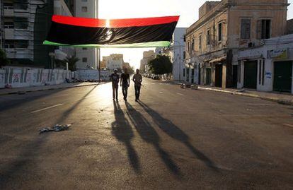 Milicianos rebeldes patrullan al amanecer por una calle de la capital, Trípoli.