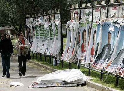 Dos viandantes miran los carteles electorales de diferentes partidos en una calle de Roma.