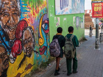 Dos estudiantes caminan frente a un mural de Nelson Mandela, este martes en Johannesburgo.