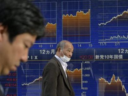 Dos hombres junto a una pantalla de la Bolsa en Tokio (Jap&oacute;n).