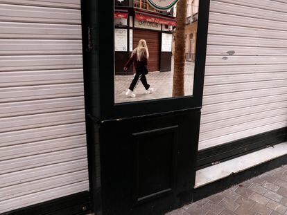 Una persona se refleja en el espejo de la fachada de un comercio cerrado este jueves en el centro de Málaga.