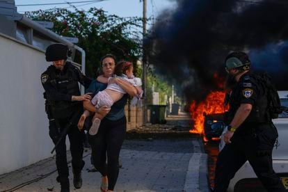 Dos policías sacan a una mujer y una niña de una zona afectada por el lanzamiento de un misil palestino en la ciudad de Ashkelón, este sábado.