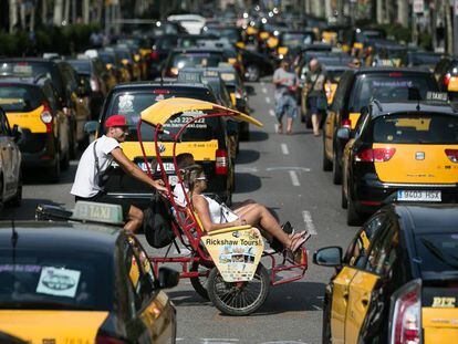 Un bici-taxi turístico cruza por la Gran Via de Barcelona, cortada por la huelga de taxistas