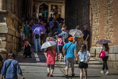 Turistas se protegen del sol mientras pasean por Toledo, que se encuentra en aviso naranja por ola de calor, este jueves.

