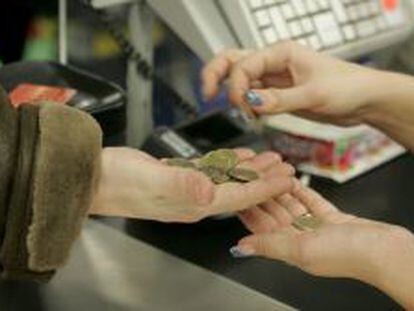 Una cajera ayuda a un cliente a contar las monedas de euro en un supermercado. EFE/Archivo