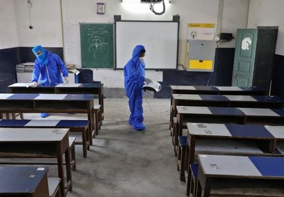 Unos trabajadores equipados con uniformes de protección desinfectan un aula de la Escuela Central Modelo en Barrackpore en las afueras de Calcuta, India, el 8 de junio de 2020.