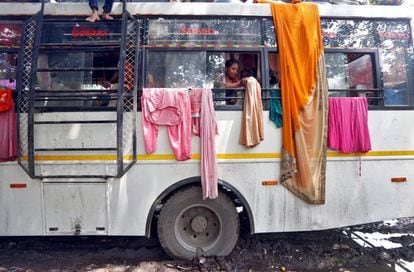 Una peregrina hindú cuelga su ropa en las barras de hierro de un autobús inmovilizado a orillas del río Ganges, en Calcuta (India).