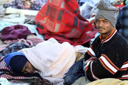 Refugiados llegados desde Libia descansan en el paso fronterizo de Ras El Jadir, en Túnez