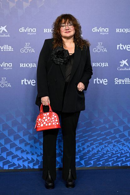 La directora Isabel Coixet, con un traje negro con una gran flor en la solapa, buscó el contraste en los complementos con un bolso rojo con lunares blancos de Louis Vouitton by Yayoi Kusama.