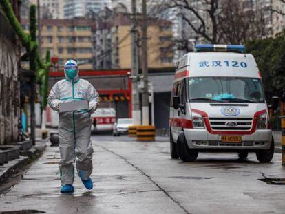 Un conductor de ambulancia con un traje protector lleva una caja con provisiones médicas en Wuhan.