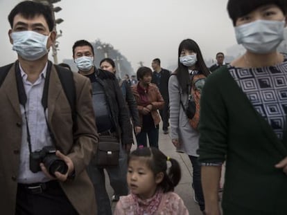 Varias personas caminan con mascarilla por la plaza de Tiananmen de Pekín, en un día de contaminación.