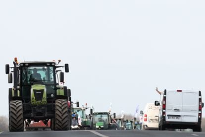 Un conductor hace el signo de la victoria desde su furgoneta mientras decenas de tractores llegan al punto de bloqueo de la carretera nacional D1001 cerca de Bornel, al norte de París.