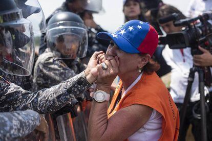 Una mujer suplica a un miembro de la Policía Nacional Bolivariana que deje pasar la ayuda humanitaria.