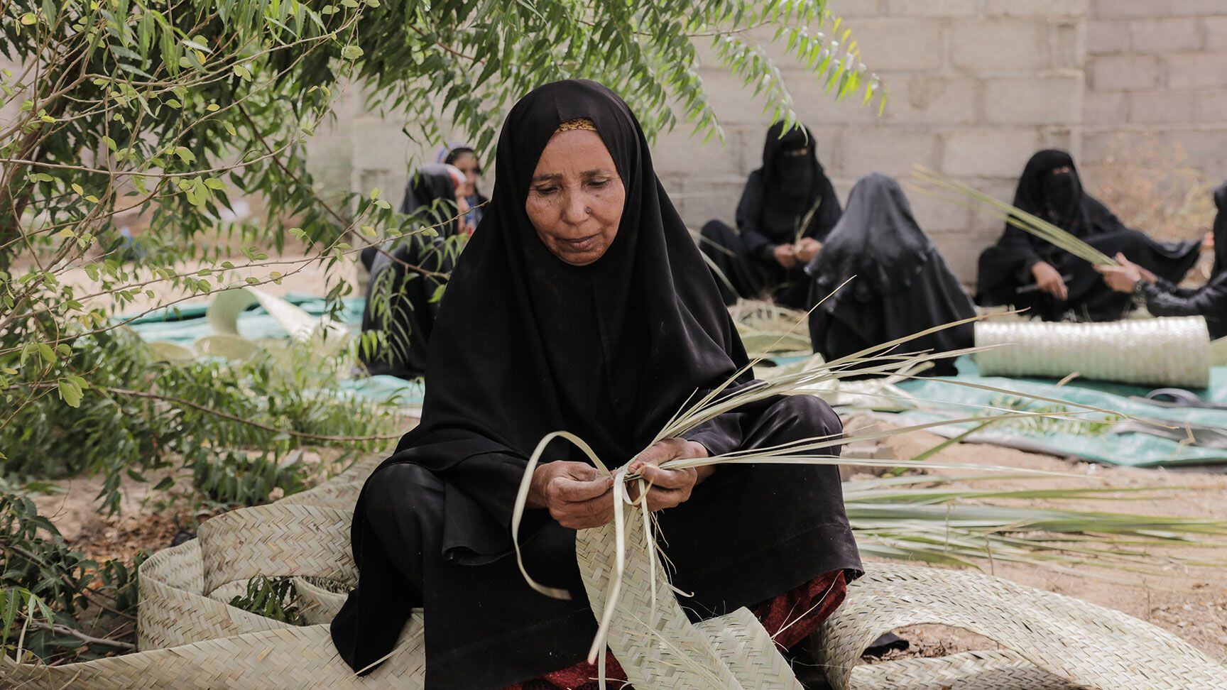 Aish Mohammed Abdo tiene 52 años y teje esteras con la fibra vegetal obtenida de una variedad de palmera local. Trabaja junto a otras mujeres desplazadas en Az Zayduyah, en Hudaydah.