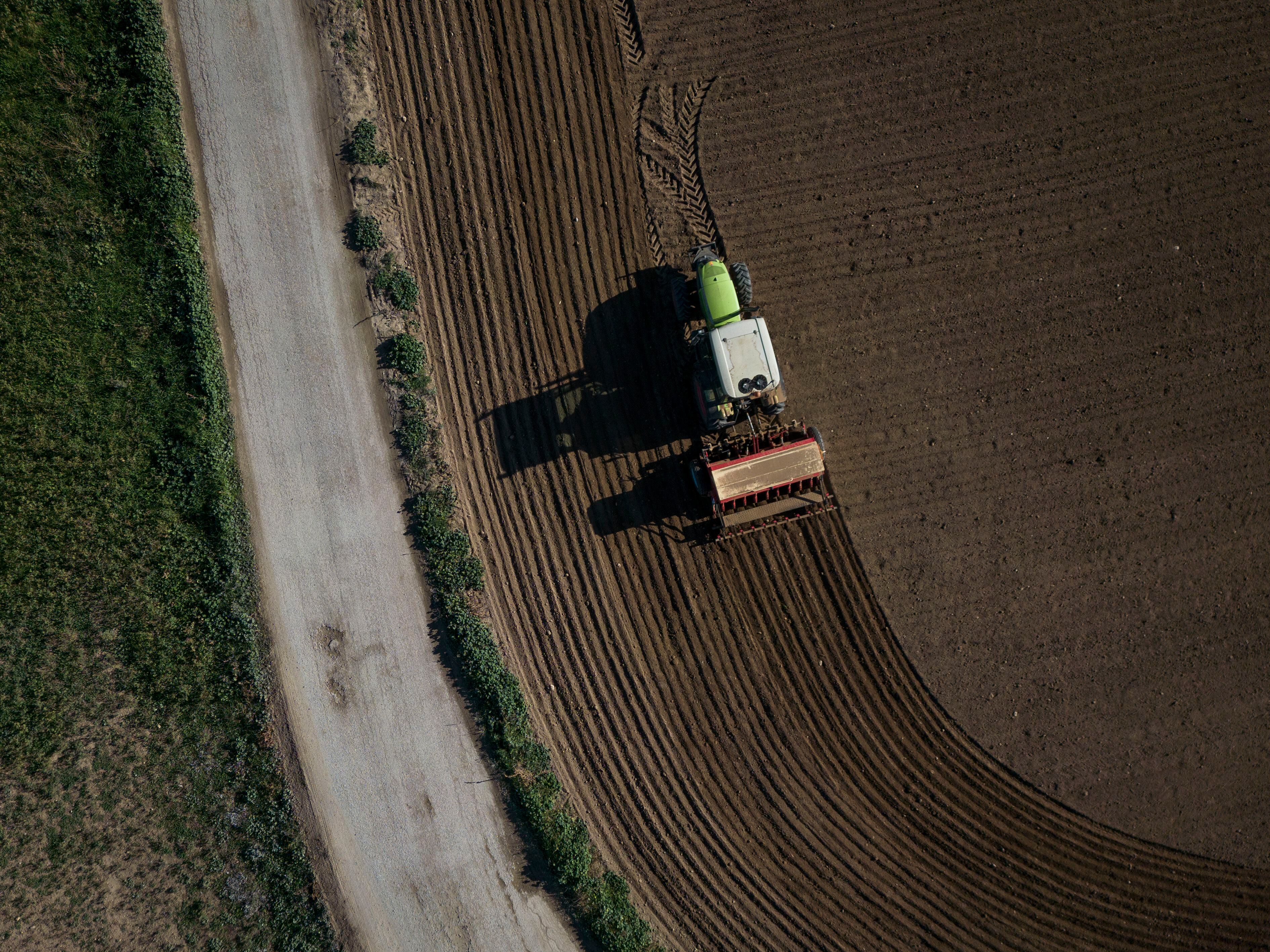 Vista cenital de un agricultor que pasa la sembradora con un tractor en un campo de cultivo de secano.