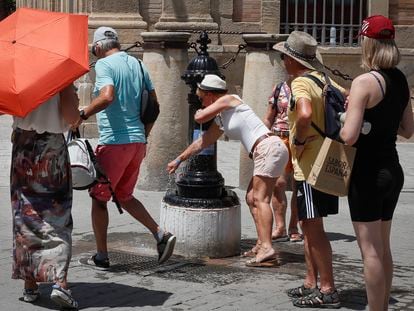 Varios turistas se refrescan en una fuente en el centro de Sevilla.