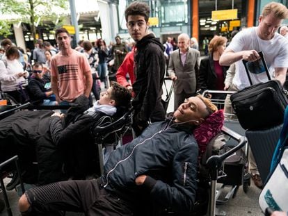 Dos jóvenes se tumban sobre sus equipajes mientras hacen cola fuera de la Terminal 5 del aeropuerto de Heathrow, en Londres, Reino Unido.