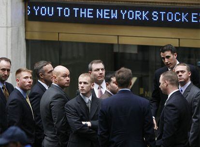 Operadores de la Bolsa de Nueva York esperan a la puerta del edificio, en Wall Street.