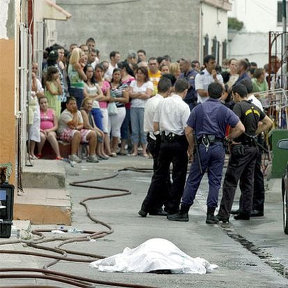 Varios miembros de la Policía junto al cadáver de la mujer fallecida en el incendio.