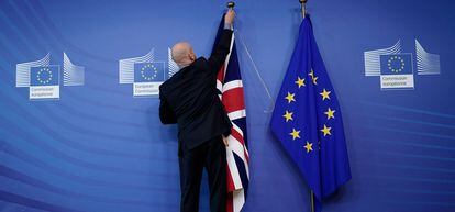 Un empleado coloca las banderas del Reino Unido y de la Unión Europea en la sede de la Comisión en Bruselas.