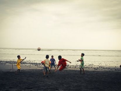 Varios niños juegan al fútbol en la playa.