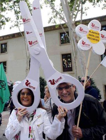Dos personas sostienen unas tijeras de gran tamaño durante una concentración, en la que han participado medio millar de sindicalistas de UGT, CCOO, INTERSINDICAL, CSIF, ANPE, SATSE, y SIME, hoy ante el Palacio de San Esteba de Murcia.