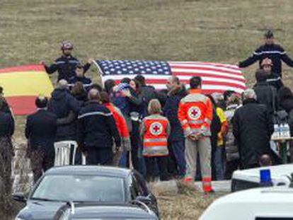 Membres dels equips de rescat despleguen banderes de les nacionalitats de les víctimes davant els seus familiars, aquest dijous a Le Vernet.