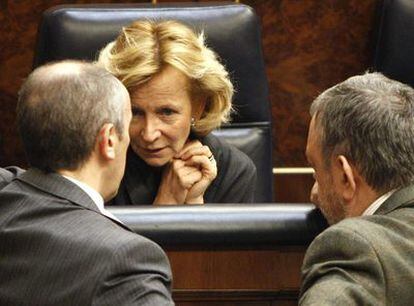 La vicepresidenta económica del Gobierno, Elena Salgado, conversa con dos diputados en su escaño del Parlamento.