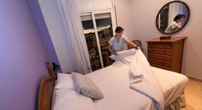 Una camarera de piso limpia una habitación y prepara la cama