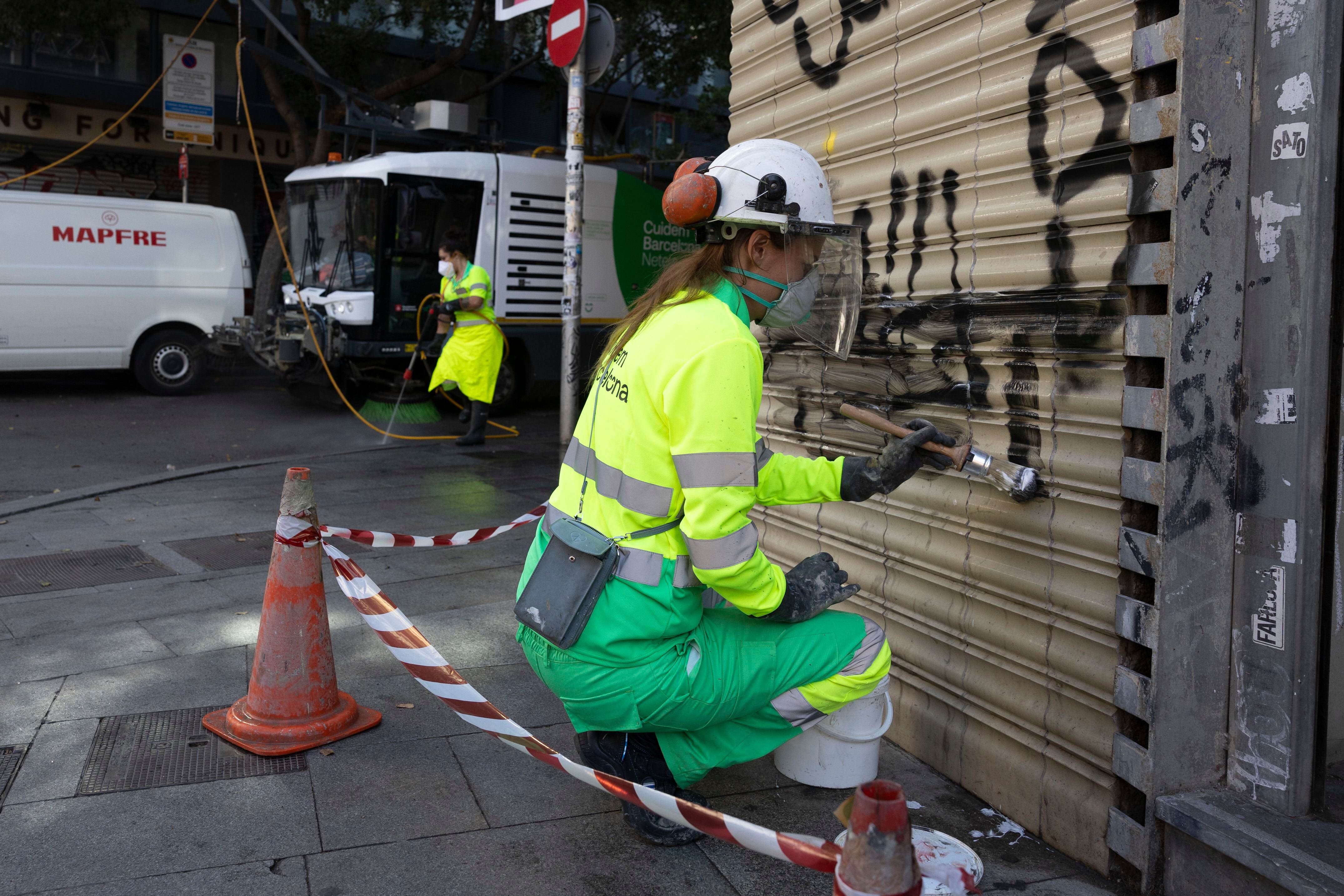Una empleada del servicio de limpieza viaria de Barcelona elimina pintadas en el barrio del Raval, este jueves.