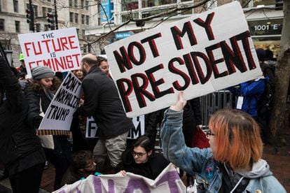 Manifestantes sujetan pancartas con consignas cerca de una de las rutas del desfile de inauguración, donde pasará el presidente electo de los Estados Unidos, Donald Trump, una vez sea investido, en Washington. 