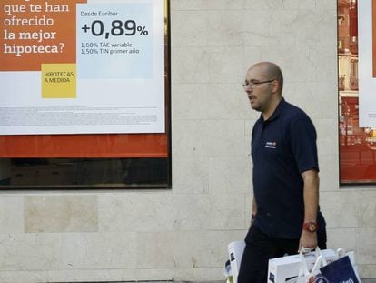 Un hombre pasa por delante de la publicidad de hipotecas de una sucursal bancaria, en Madrid.