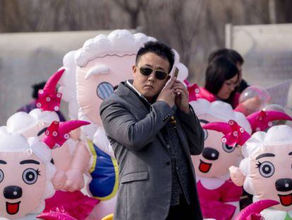 Un hombre llama por teléfono delante de muñecos de Pleasant Goats, una serie animada de televisión china