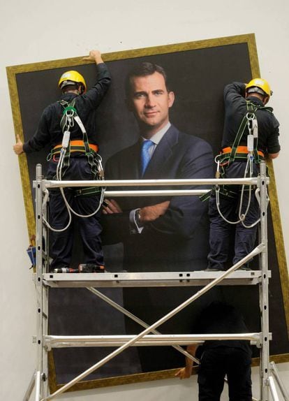 Dos técnicos municipales durante la instalación de la gran foto del rey Felipe VI que preside desde el Salón de Plenos del Palacio de Cibeles, el 24 de junio de 2014.