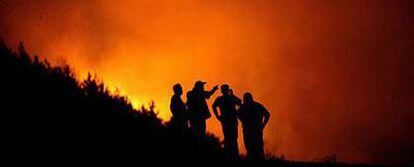 Bomberos y residentes de la villa de Kukurecani, en Macedonia, observan un incendio forestal.