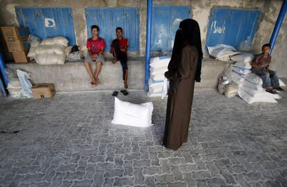 Unos palestinos esperan a recibir sacos de harina en el campo de refugiados de Shati, en Gaza.